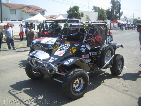 1990 Ford Bronco - Front view of a black tube-frame off-road buggy number 1804 with a steel brush guard and KC lights staged among other vehicles.
