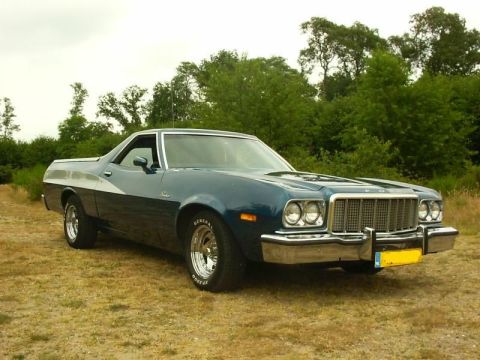 1973 Ford Ranchero - This blue 1974 Ford Ranchero pickup truck is shown from a three-quarter front angle in a grassy outdoor setting.