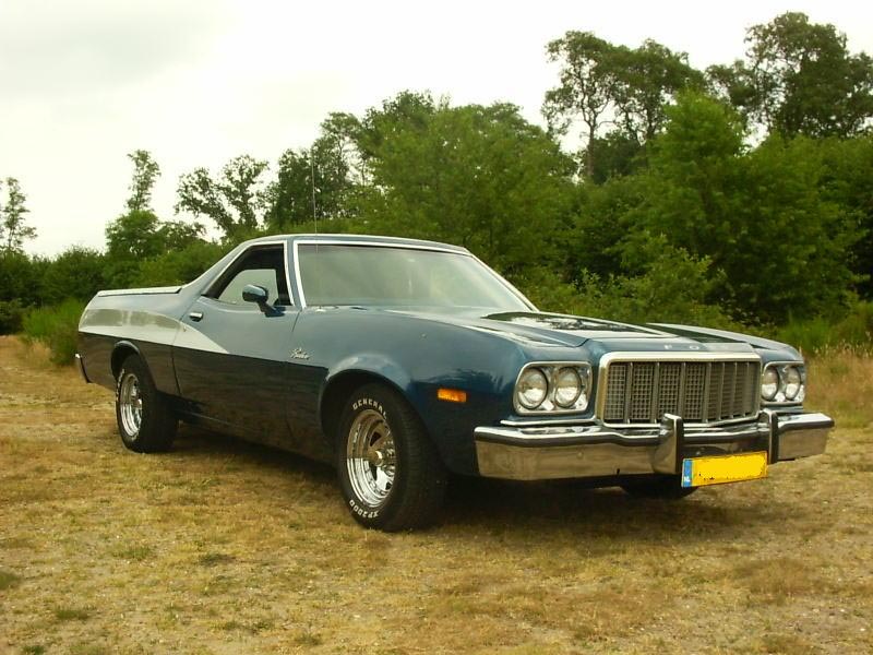 Blue 1974 Ford Ranchero pickup truck with chrome grille and bumper, parked on grassy field