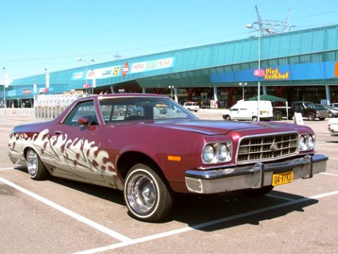 1973 Ford Ranchero - Custom 1973 Ford Ranchero with flame graphics parked in a lot, showing its distinctive grille and front end.