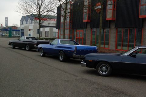 1973 Ford Ranchero - Three Ford Rancheros are parked in a row on a street in front of a building.