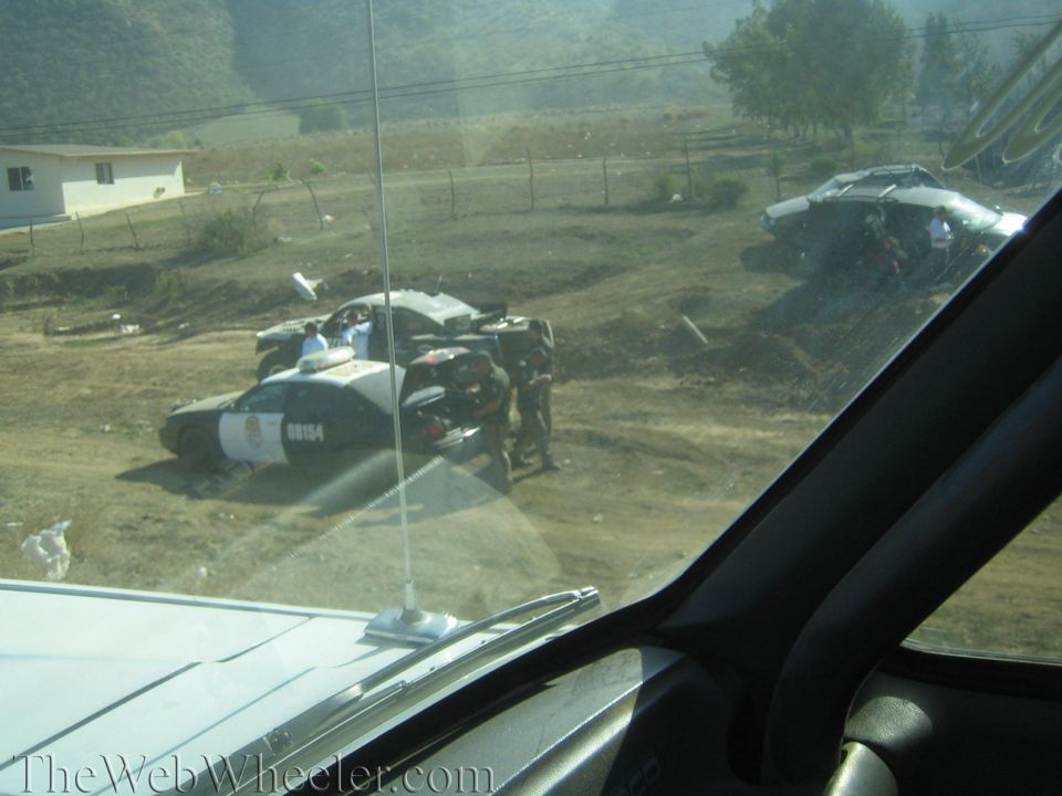 Police car and off-road vehicle in a dirt lot seen through a windshield