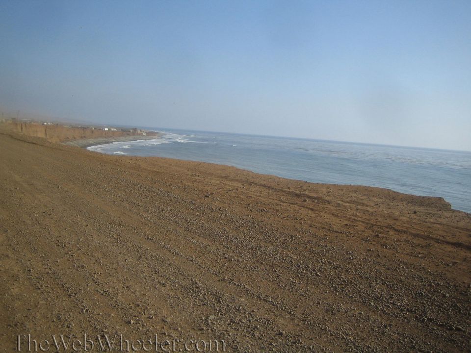 Gravelly coastal bluff overlooking the ocean under a hazy sky