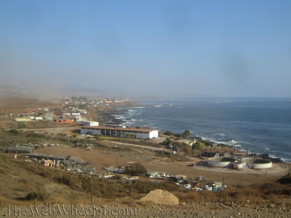 Coastal town and shoreline viewed from a hilltop with haze over the ocean