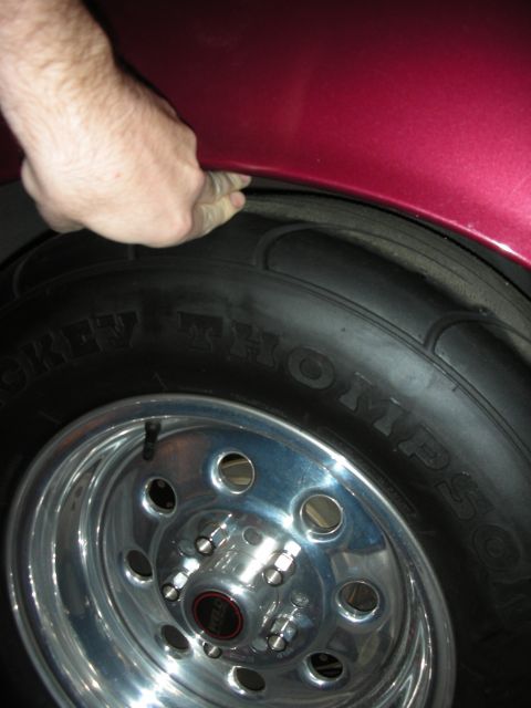 1992 Ford Crown Victoria - A hand checks the tire clearance in the wheel well of a red vehicle.