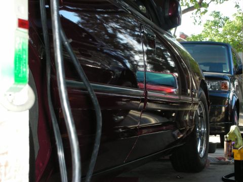 1992 Ford Crown Victoria - Side view of a dark red sedan with chrome trim, parked next to another vehicle.