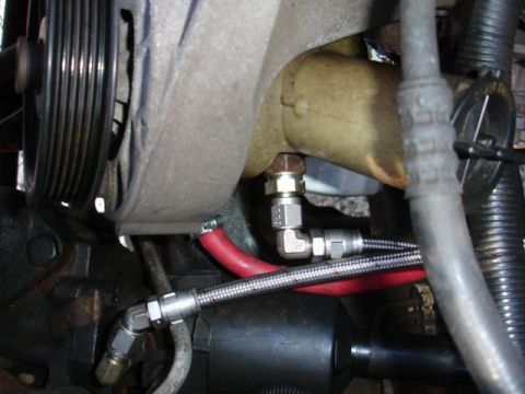 1996 Ford Bronco - Close-up view of vehicle power steering pump with connected hoses and lines.