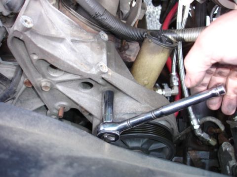 1996 Ford Bronco - A socket wrench is used to turn an engine pulley, likely for maintenance or repair.