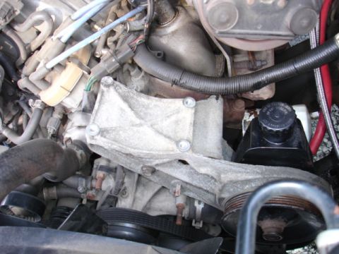 1996 Ford Bronco - Close-up view of engine components including a bracket, pulleys, and hoses.