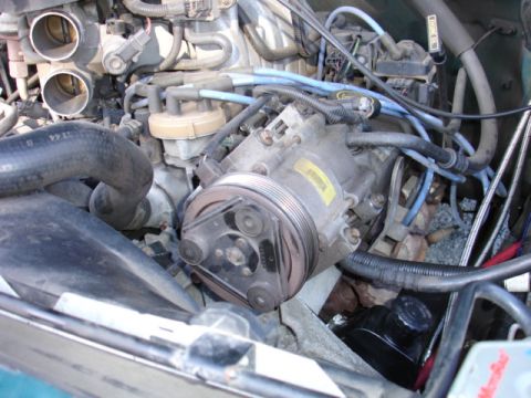 1996 Ford Bronco - Close-up view of the engine bay, focusing on the air conditioning compressor and associated engine components.