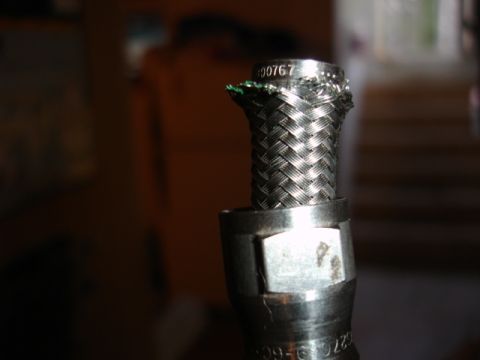 1996 Ford Bronco - Close-up of a braided metal hose fitting with visible text and some green wire.