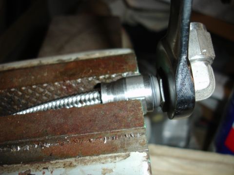 1996 Ford Bronco - A close-up view shows a metal hose fitting being secured in a vise and tightened with a wrench.