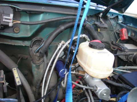1996 Ford Bronco - Close-up view of the engine bay, focusing on the brake fluid reservoir and associated plumbing.
