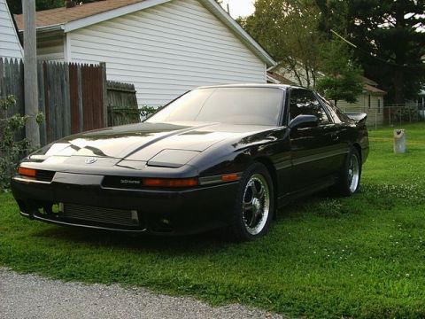 1994 Ford Probe - This black coupe features pop-up headlights and a '3.0 TURBO' badge, indicating it is likely a Toyota Supra from the early 1990s.