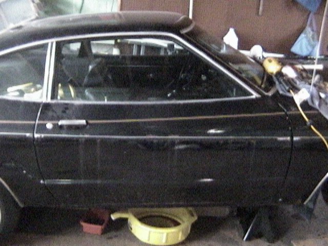 1977 Ford Mustang side view, black coupe with gold trim
