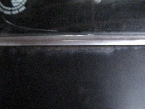 1977 Ford Mustang - Close-up of car interior trim, showing a chrome accent strip and a partial emblem.