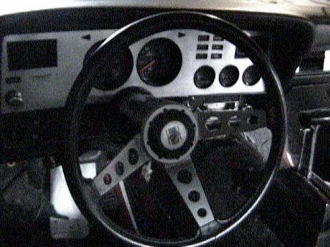 1977 Ford Mustang - The interior of a 1977 Ford Mustang II shows a silver dashboard with gauges and a three-spoke steering wheel.