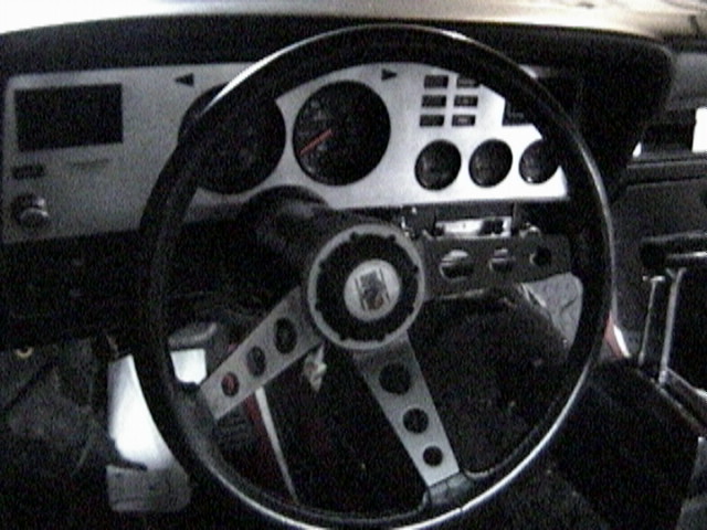 1977 Ford Mustang II interior with a three-spoke steering wheel and a silver dashboard