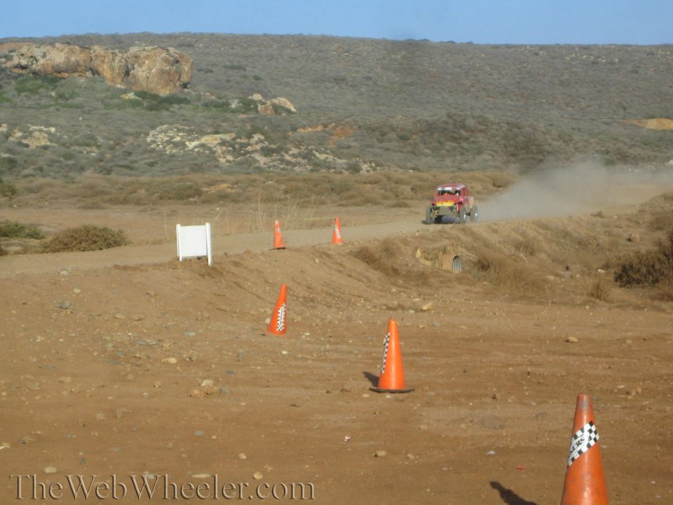 Distant off-road vehicle raising dust on a coned desert dirt course