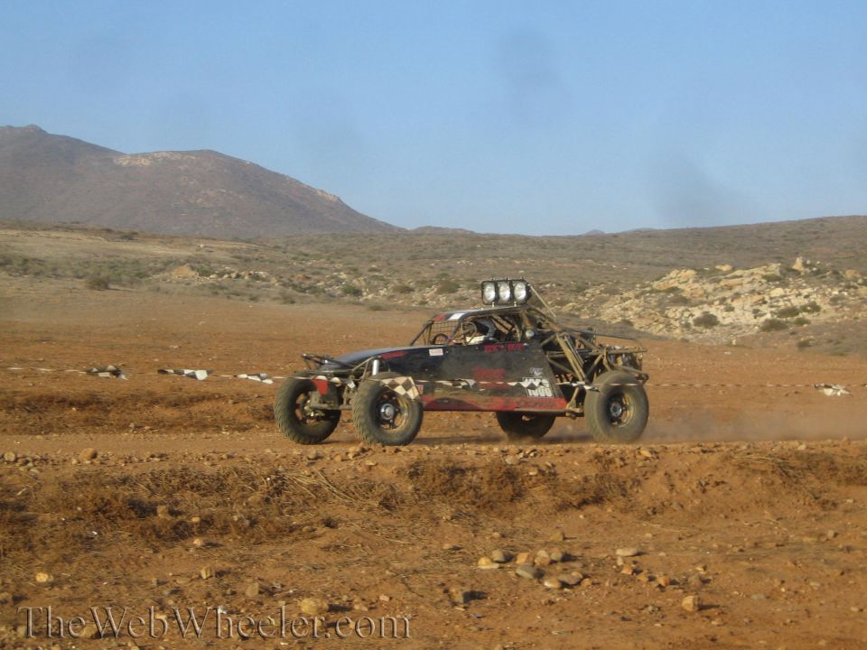 Dark off-road race buggy with roof light bar racing in open desert