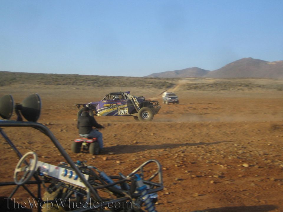 Purple race buggy number 1015 jumping as spectator on quad watches