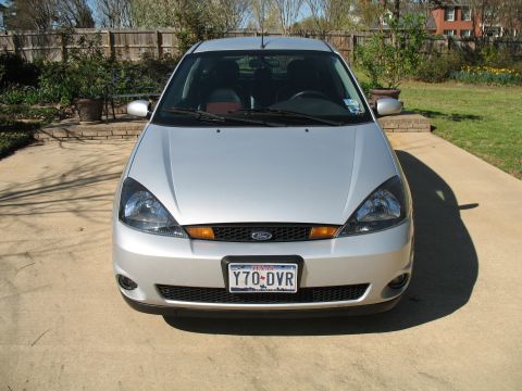 1993 Ford Bronco - This silver Ford Focus is shown from the front, parked on a concrete driveway with a wooden fence and greenery in the background.