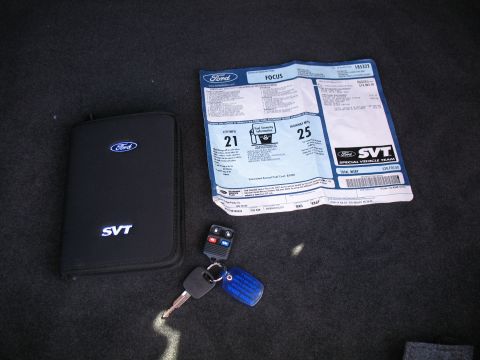 1993 Ford Bronco - Window sticker and owner's manual for a Ford SVT Focus, along with car keys, are laid out on a dark carpeted surface.
