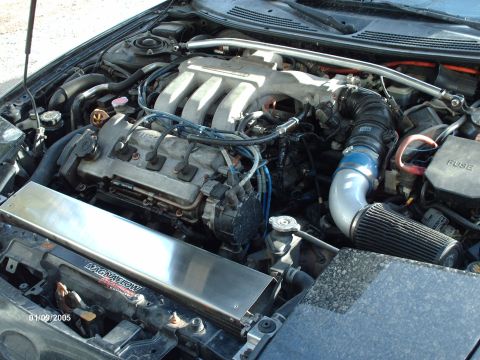 1995 Ford Probe - The engine bay of a vehicle, a V6 engine with an aftermarket air intake system and a Magnaflow cover.