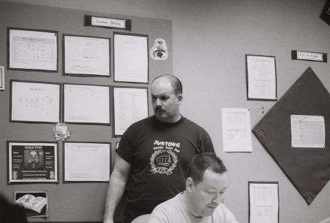 1973 Ford Ranchero - Bulletin boards with various documents and signs are displayed on a wall behind two men.