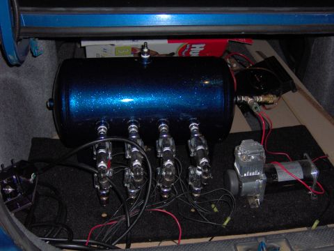 1996 Chevrolet Cavalier - Custom air suspension system components, including a sparkly blue tank and compressor, are installed in the trunk of a vehicle.