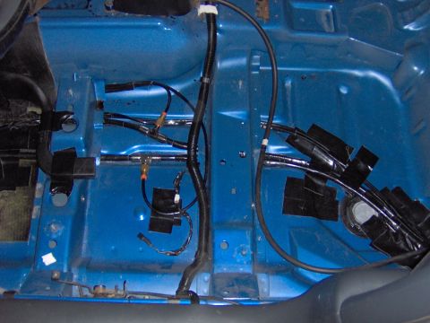1996 Chevrolet Cavalier - The interior floor of a vehicle shows a complex network of wires and tubing, some secured with black tape.