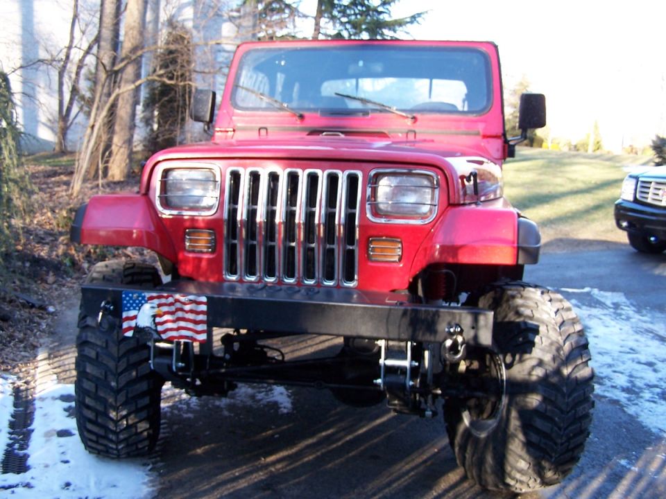 Red lifted Jeep Wrangler with American flag on bumper, front view