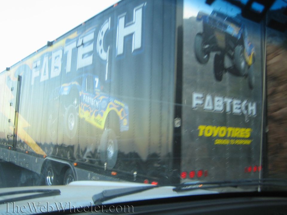 Side of black Fabtech trailer with truck graphics seen through windshield