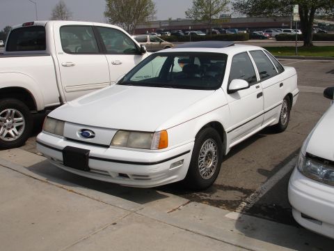 1993 Ford Taurus - A white 1992 Ford Taurus is parked in a lot, with a pickup truck and another car nearby.