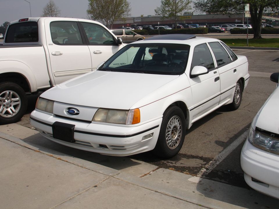 White 1992 Ford Taurus sedan parked next to a white pickup truck and another white car
