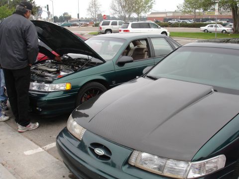 1993 Ford Taurus - Two sedans parked side-by-side, one green with its hood open, revealing the engine.