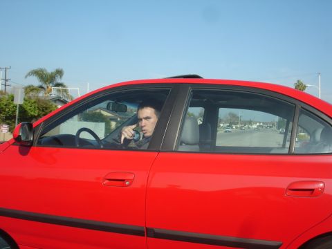 1993 Ford Taurus - Driver in a red sedan looks out the window while on a street.