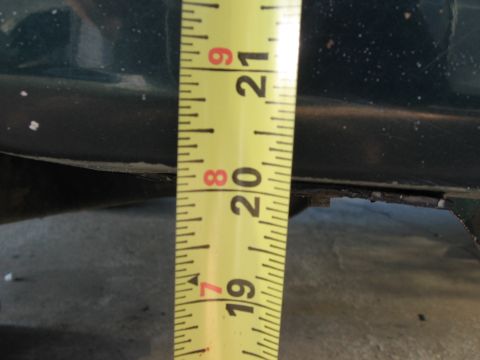 1974 Ford F-100 - A close-up view of a measuring tape against the frame of a dark green vehicle, indicating a lift measurement.
