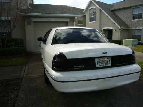 2000 Ford Crown Victoria - Rear view of a white 2000 Ford Crown Victoria with tinted taillights and a Florida license plate parked in front of a residential garage.