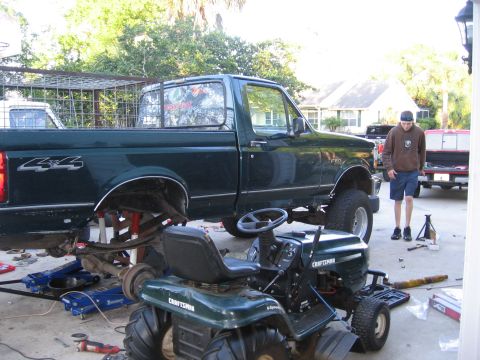 1974 Ford F-100 - A dark green pickup truck is shown lifted on jacks with its rear axle removed, suggesting ongoing maintenance or modification.