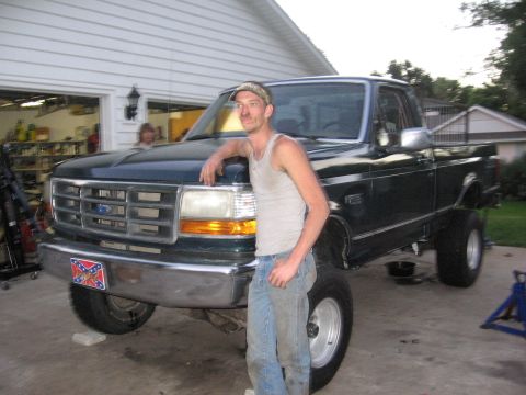 1974 Ford F-100 - A man poses with his lifted Ford F-150 pickup truck in front of a garage.