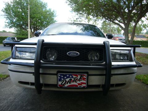 2000 Ford Crown Victoria - Front view of a 2000 Ford Crown Victoria, equipped with a push bar and a D.A.R.E. license plate. Another vehicle is parked in the backgroun…