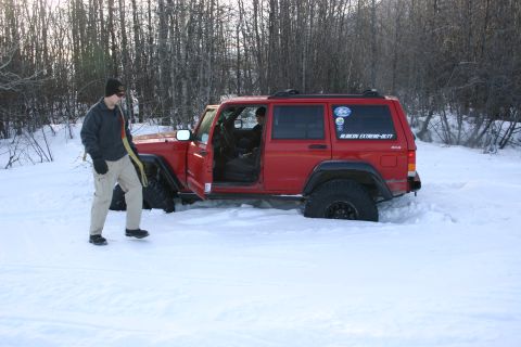 2003 Jeep TJ - Jeep Cherokee XJ stuck in snow with a person preparing to tow it out.