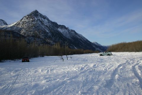 2003 Jeep TJ - Two SUVs are parked in a vast, snow-covered area with a mountain range in the distance under a clear blue sky.