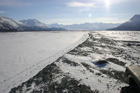 2003 Jeep TJ - A Jeep's front corner is visible in a vast, snowy valley with mountains in the background.