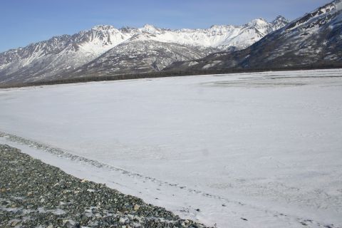 2003 Jeep TJ - A vast, snow-covered plain stretches towards , snow-capped mountains under a clear blue sky.