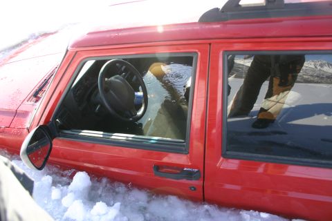 2003 Jeep TJ - A red Jeep Cherokee is partially submerged in water and snow, with the interior flooded. The vehicle appears to be stuck.
