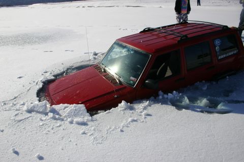 2003 Jeep TJ - A red Jeep Cherokee XJ is partially submerged in ice, with its front end sunk deep into the frozen surface.