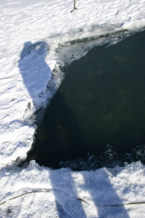 2003 Jeep TJ - Shadows of people are cast on the snow and ice surrounding a dark body of water.