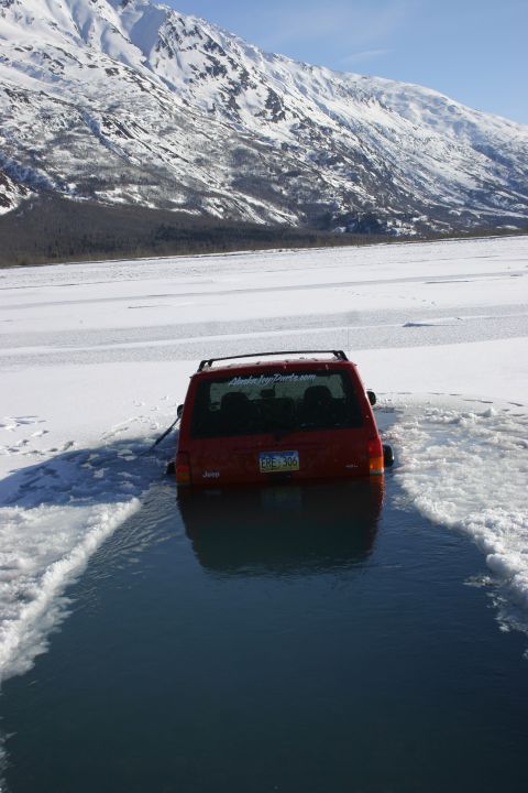 2003 Jeep TJ - Jeep submerged in icy water near snowy mountains.